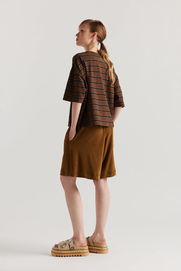 Back view of model in the black/brown/lilac stripe, Obelisk Feeder Stripe Tee in yarn-dyed slub cotton with relaxed boxy fit