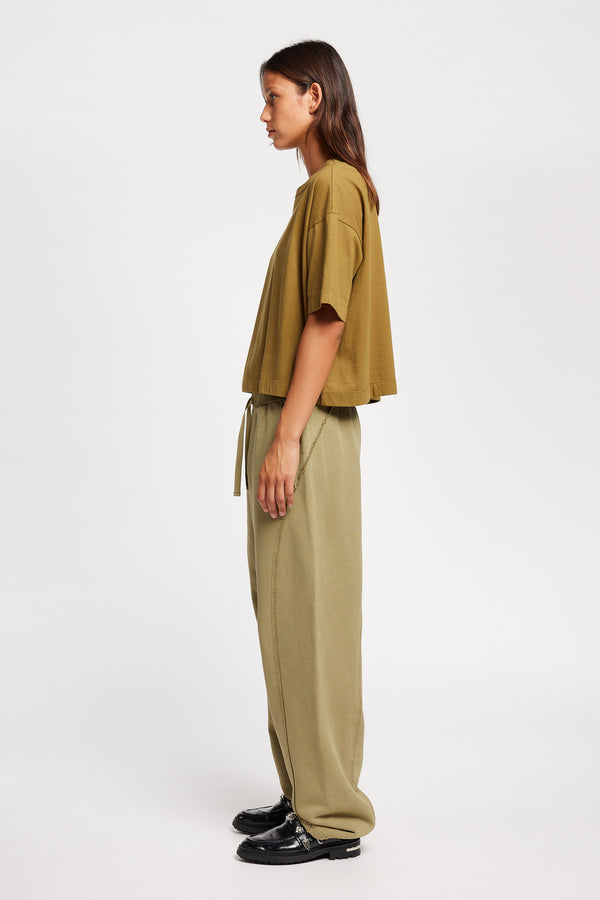 Side view of Model wearing Obelisk Tee in Olive Oil, showcasing oversized silhouette and dropped shoulders