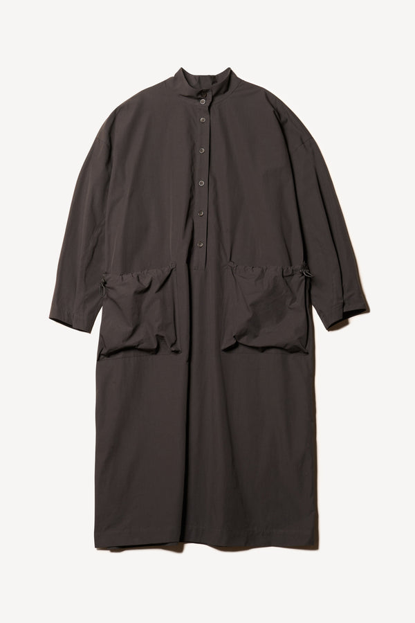 Flat front of the Odeum Dress in black mid-weight cotton, featuring a high mock collar and large utility pockets.