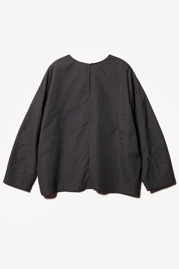 Flat Back of the Omit Top, a relaxed-fit Japanese seersucker top in Jet Black with dropped sleeves and a round neckline.