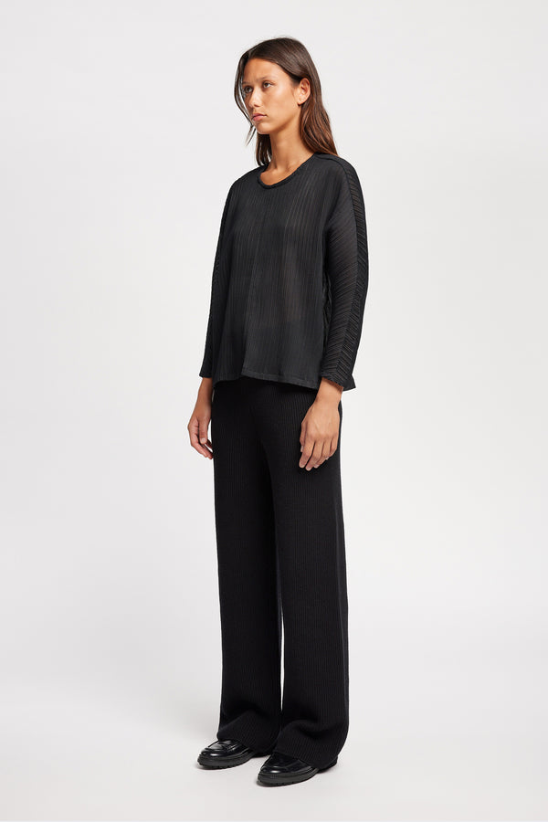 Front of Model wearing the Loose-fit crinkle top in black made from Japanese recycled polyester, featuring panelled seams and a textured finish.