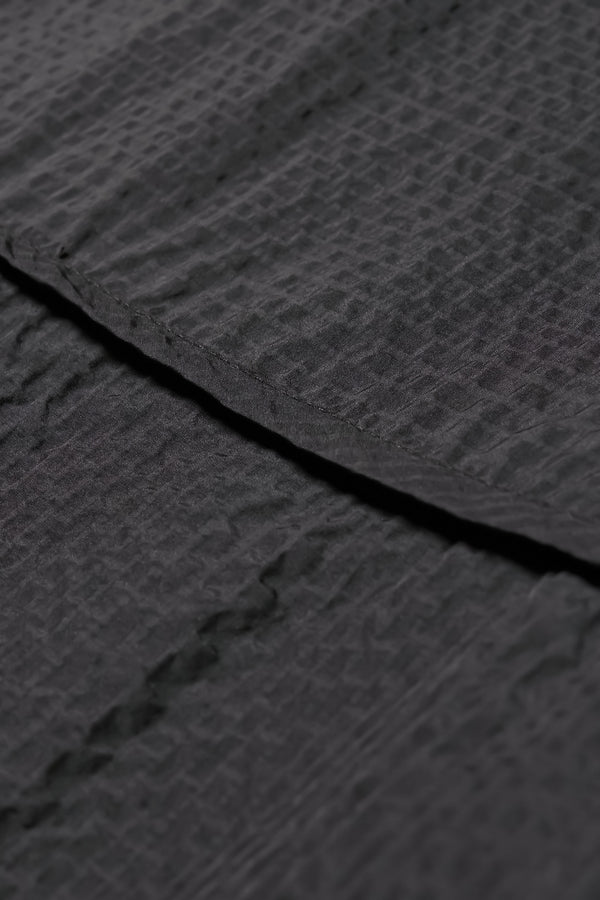 Close up fabric shot of  the Omit Top, a relaxed-fit Japanese seersucker top in Jet Black with dropped sleeves and a round neckline.