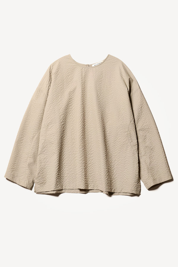 Flat Front of the Omit Top, a relaxed-fit Japanese nylon seersucker top in Stone/ beige with dropped sleeves and a round neckline.