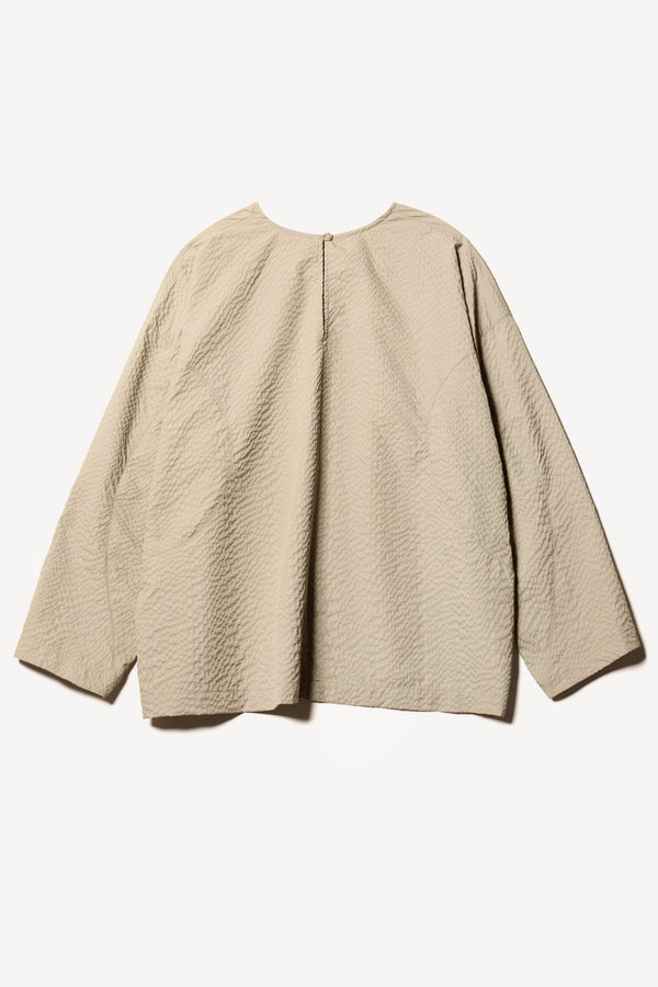 Flat Back of the Omit Top, a relaxed-fit Japanese nylon seersucker top in Stone/ beige with dropped sleeves and a round neckline.