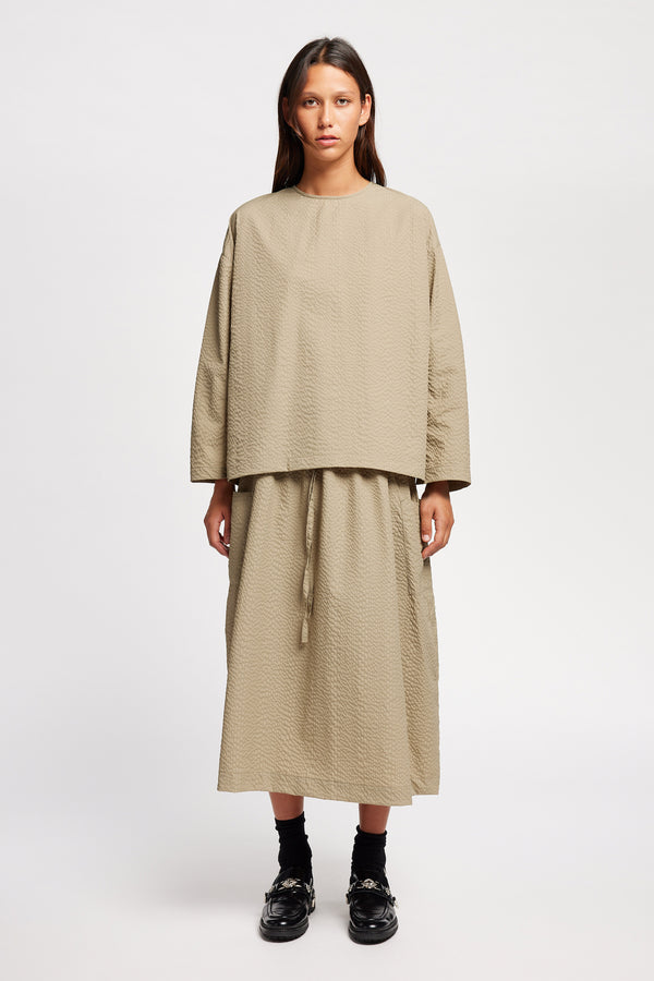 Front of the Model wearing the Omit Top a relaxed-fit Japanese nylon seersucker top in Stone/ beige with dropped sleeves and a round neckline.