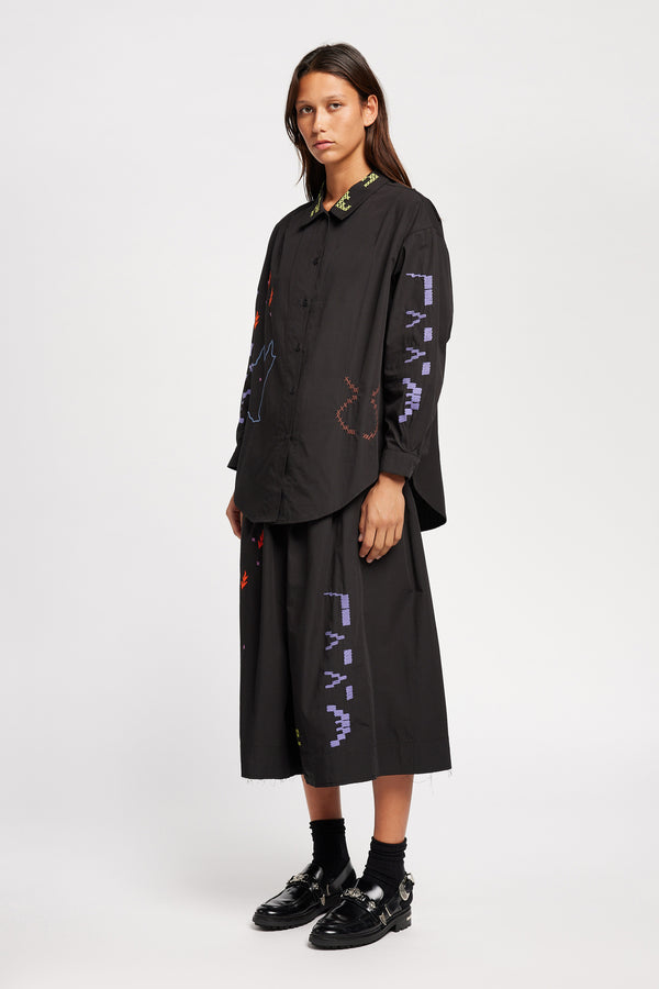 Front of model wearing Black One World shirt with embroidered Arecibo motifs on collar, sleeves, and front. Classic collar and full placket.