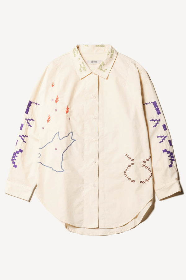 Flat front of Ecru One World Shirt with embroidered Arecibo motifs on collar, sleeves, and front. Classic collar and full placket.