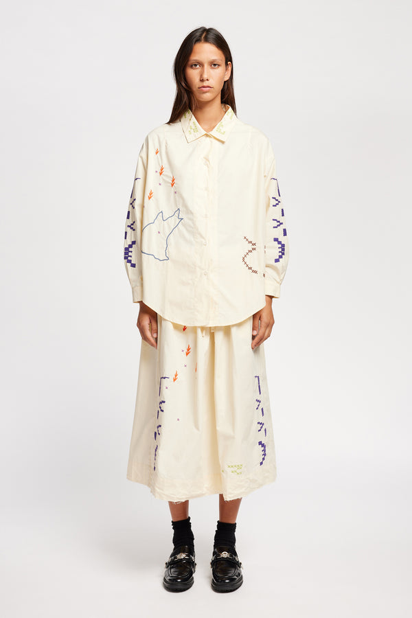 Front of model wearing Ecru button-up shirt with embroidered Arecibo motifs on collar, sleeves, and front. Classic collar and full placket.