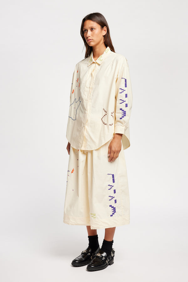 Front of model wearing Ecru button-up shirt with embroidered Arecibo motifs on collar, sleeves, and front. Classic collar and full placket.