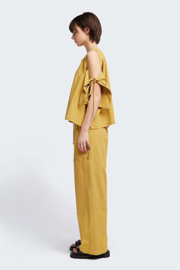 Side view of the Open Shoulder Top in mustard. Featuring a relaxed fit and side-tie sleeve details.