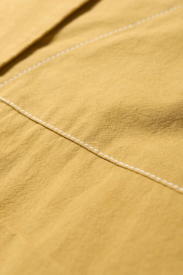 Close up fabric view of the Open Shoulder Top in mustard. Featuring a relaxed fit and side-tie sleeve details.