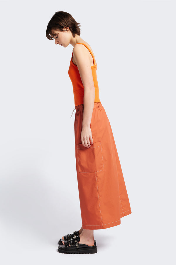 Side profile of the Opus Skirt, a straight, mid-length style skirt in Rust. Features side patch pockets and an elasticated waist for comfort. 