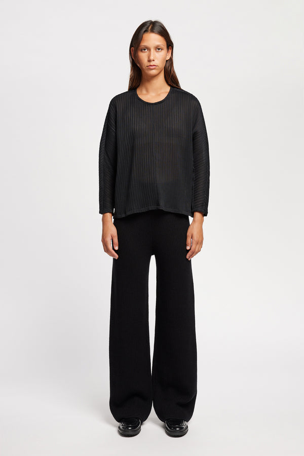 Front of Model wearing the Loose-fit crinkle top in black made from Japanese recycled polyester, featuring panelled seams and a textured finish.