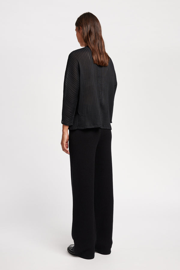 Back of Model wearing the Loose-fit crinkle top in black made from Japanese recycled polyester, featuring panelled seams and a textured finish.