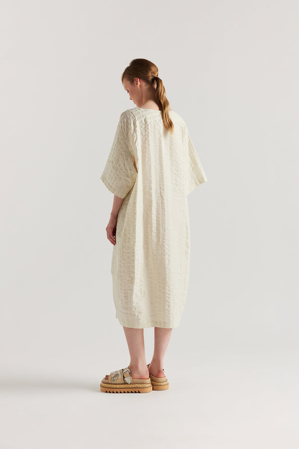 Back view of Woman wearing the Origin Dress in gingham seersucker butter check. A relaxed silhouette with internal tie, clean neckline, and subtle underarm split detail.