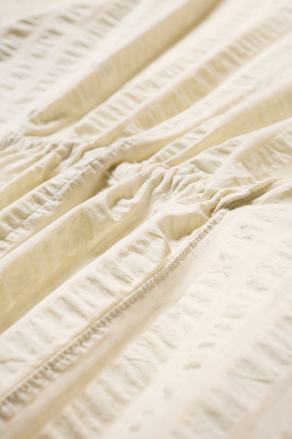 Fabric and details shot of the Origin Dress in gingham seersucker butter check. A relaxed silhouette with internal tie, clean neckline, and subtle underarm split detail.