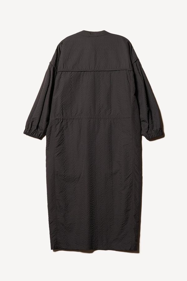 Flat Back of the Parapet Dress in Jet Black. A lightweight seersucker nylon, showing band collar and adjustable front waist tie.