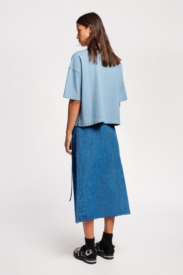 Back of Model wearing Obelisk Tee in blue, showcasing oversized silhouette and dropped shoulders