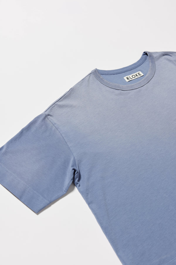 detail shot of Passage Tee in blue fade, showing relaxed fit and straight hem with side split