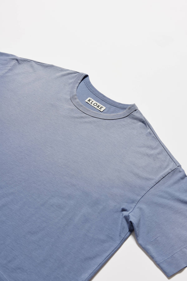 details shot of Passage Tee in blue fade, showing relaxed fit and straight hem with side split
