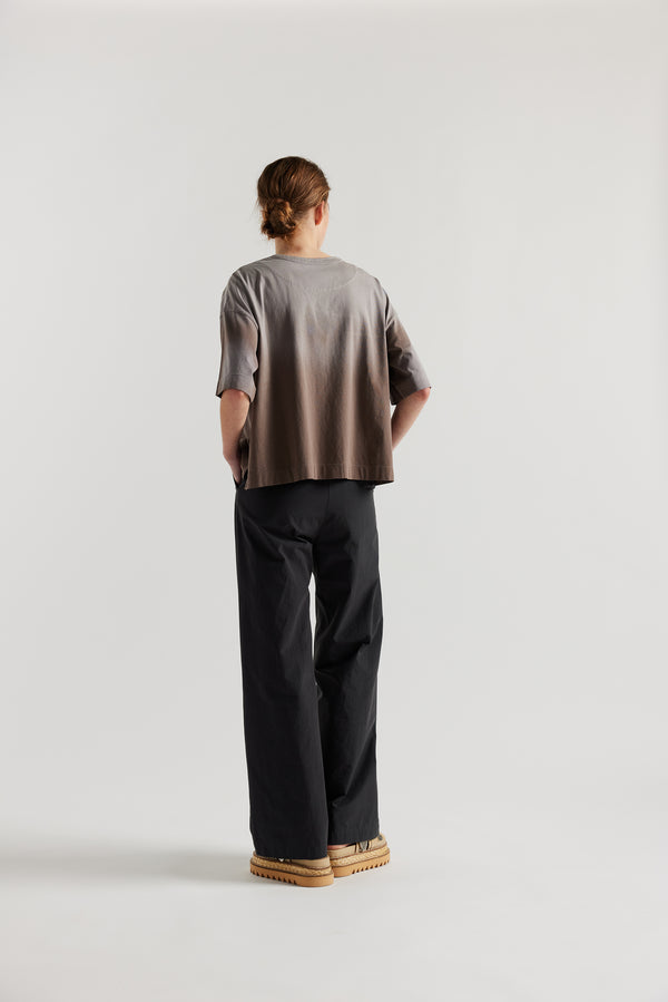 Back of Model wearing Passage Tee in brown, showcasing oversized silhouette and dropped shoulders