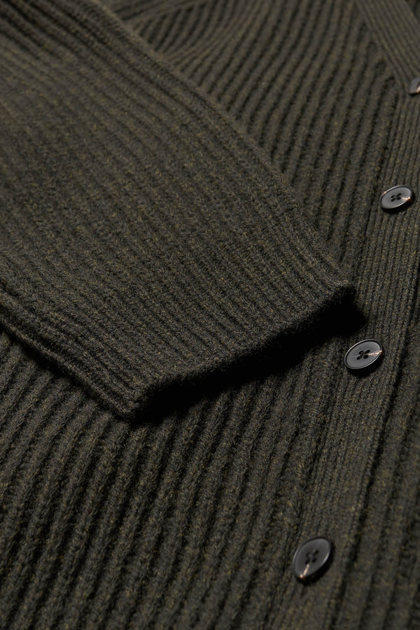 Close up fabric details of the oversized ribbed wool cardigan with button closure in darkest green