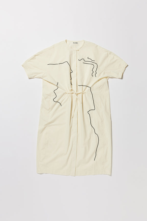 Flat front of the ecru Pensive Dress with black embroidered motifs and highlighting the encased self tie waist cinched in