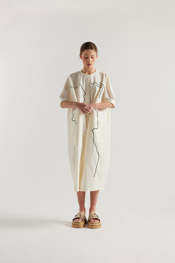 front view of female model in the ecru Pensive Dress with black embroidered motifs and round neckline