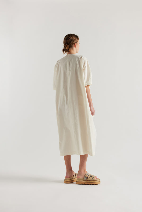 back view of female model in the ecru Pensive Dress with black embroidered motifs and round neckline