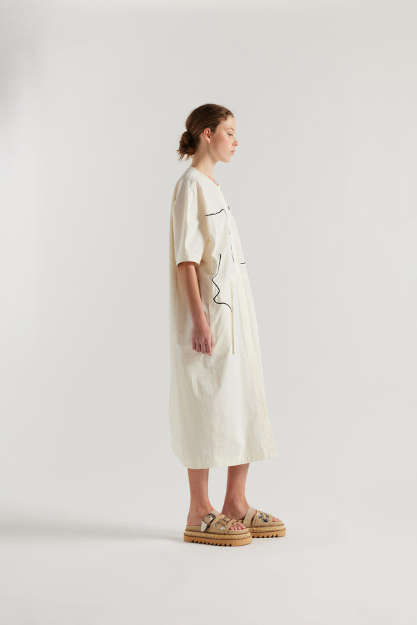 side view of female model in the ecru Pensive Dress with black embroidered motifs and round neckline