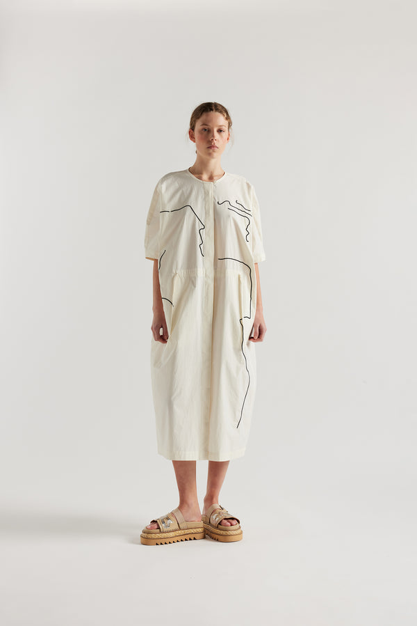 front view of female model in the ecru Pensive Dress with black embroidered motifs and round neckline