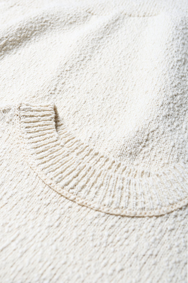 Close up details of the ecru Sleeveless textured Picknicker knit vest in soft chunky cotton, featuring ribbed trim and a 5-gauge cotton slub knit construction.