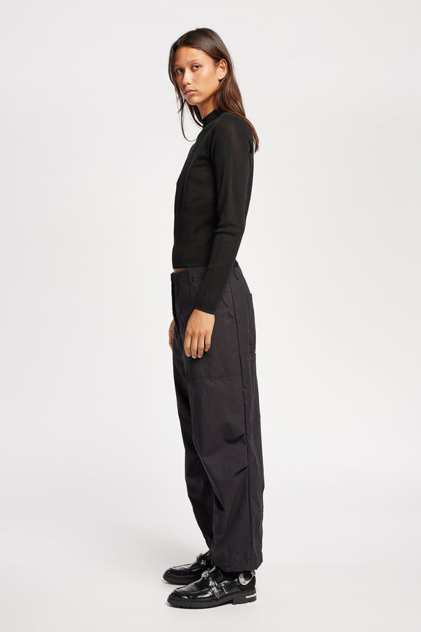 Side of Model wearing the Premise Cargo in Jet Black, a relaxed-fit pant with adjustable waistband, clean front pleats, and straight-leg silhouette.