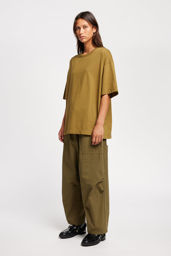 Side of Model wearing the Premise Cargo in Kelp Green, a relaxed-fit pant with adjustable waistband, clean front pleats, and straight-leg silhouette.