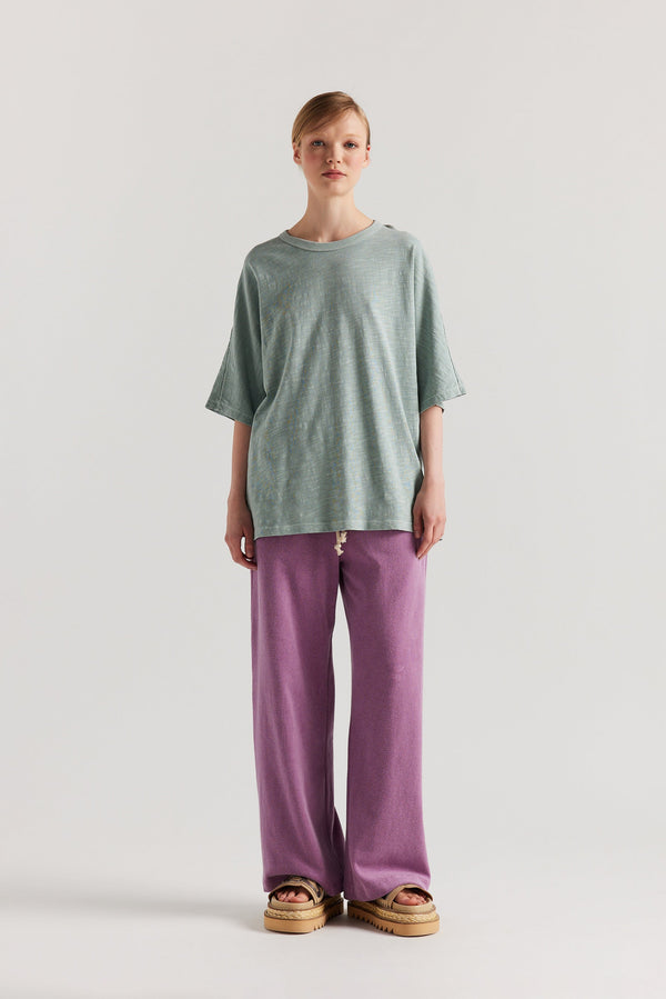 Front view of slouchy track pants in purple cotton terry with straight-leg fit and cord-tie waistband.