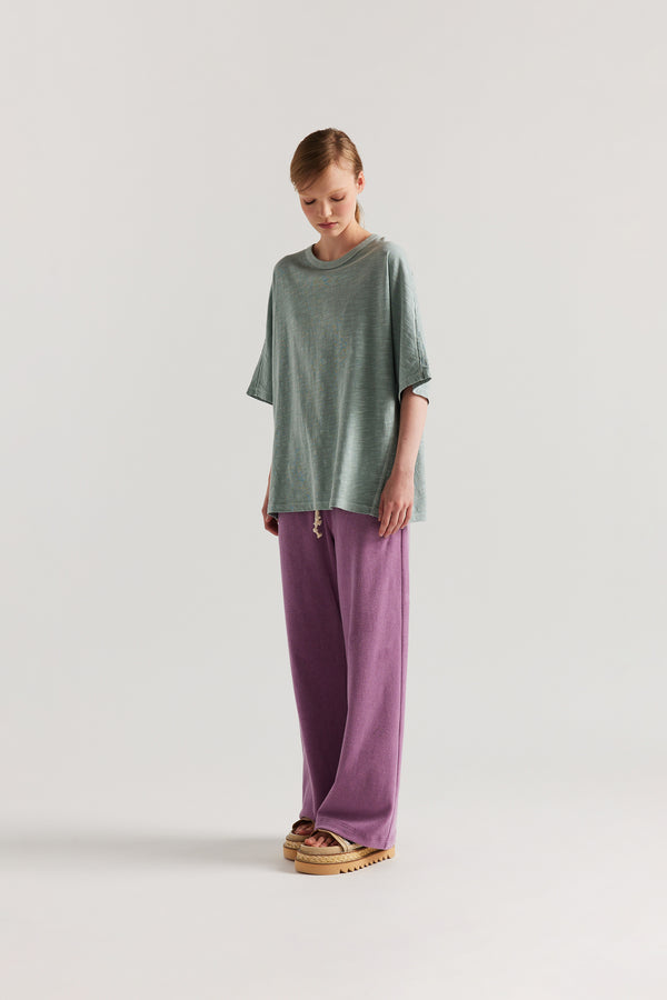 Front view of slouchy track pants in purple cotton terry with straight-leg fit and cord-tie waistband.