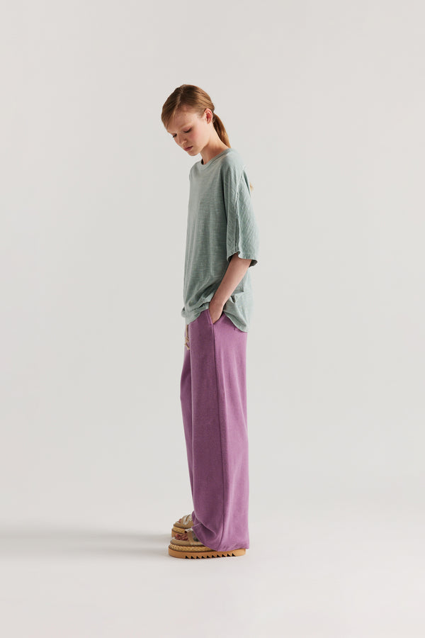 Side view of slouchy track pants in cotton terry with straight-leg fit and cord-tie waistband.