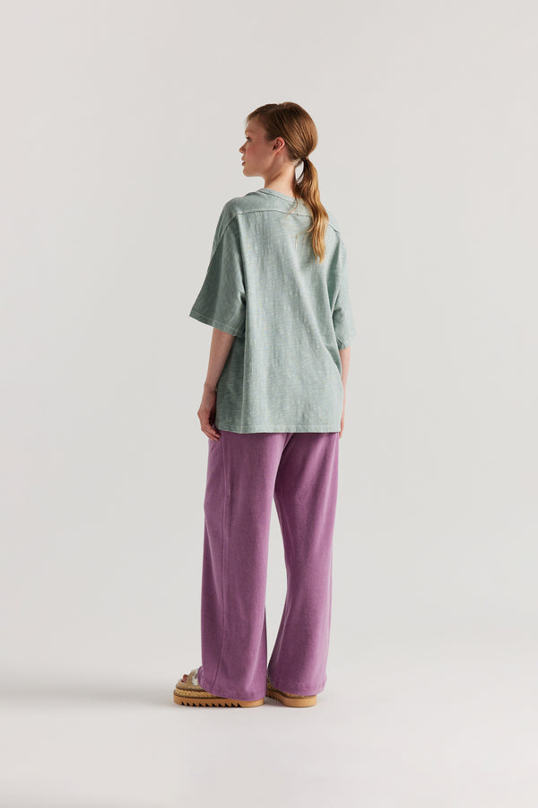 Front view of slouchy track pants in purple cotton terry with straight-leg fit and cord-tie waistband.