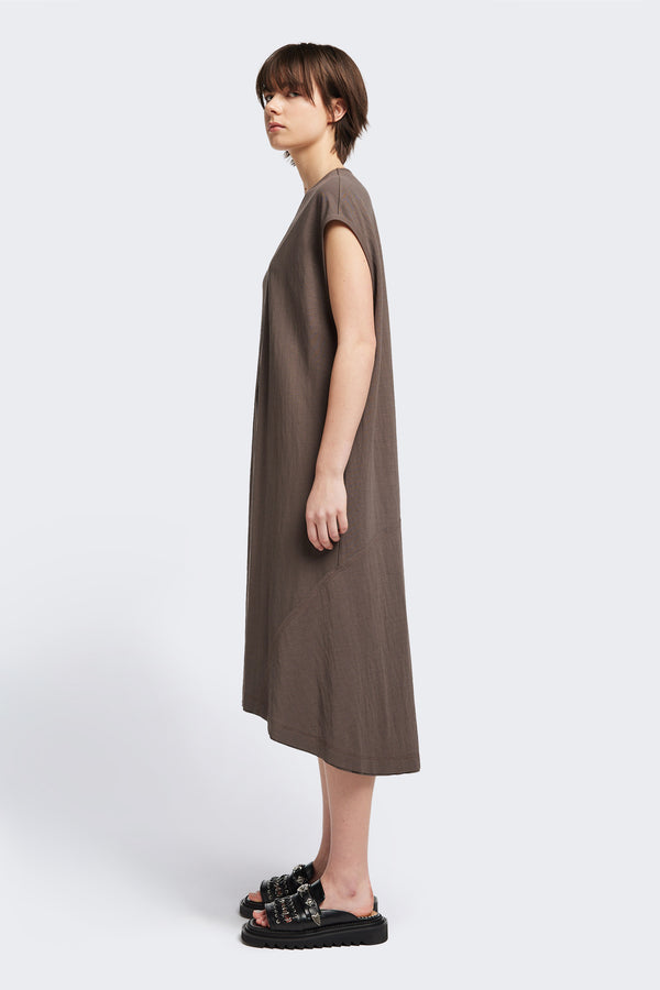 Side of the Recess dress in taupe, a sleeveless crew-neck midi dress with exposed seams, raw-edge finish, and a relaxed silhouette that falls just below the knees, offering a versatile look for casual or elevated occasions.