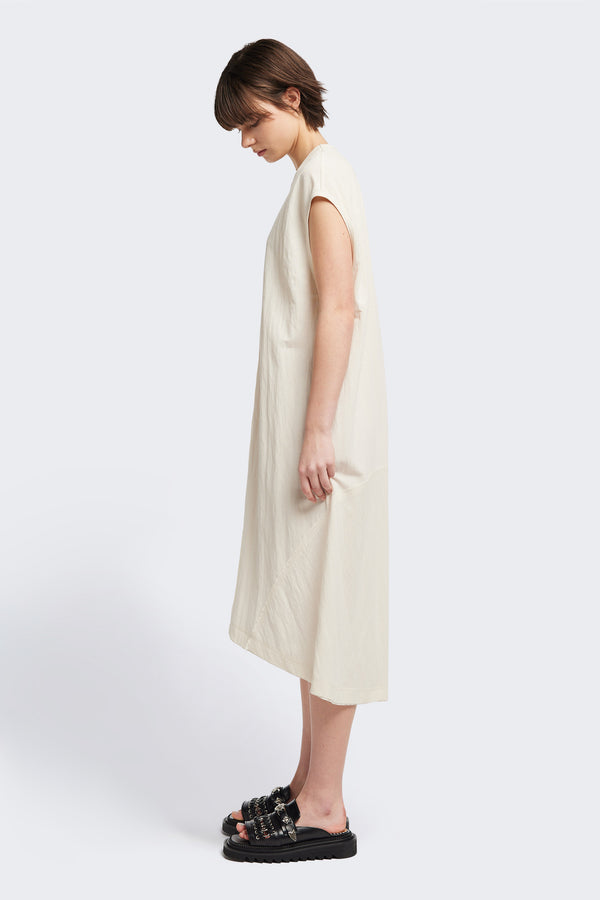 Side of the Recess dress in ecru, a sleeveless crew-neck midi dress with exposed seams, raw-edge finish, and a relaxed silhouette that falls just below the knees, offering a versatile look for casual or elevated occasions.