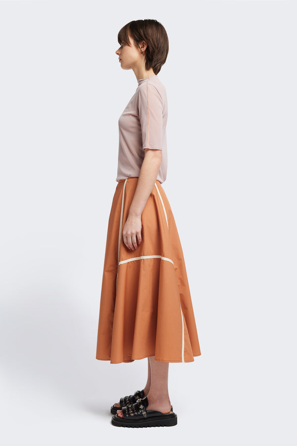 Side of the burnt orange/Ecru Regarder Bound Skirt in a lightweight cotton fabric, featuring a fuller silhouette with contrast bound seam details, midi length, and a back invisible zip closure.