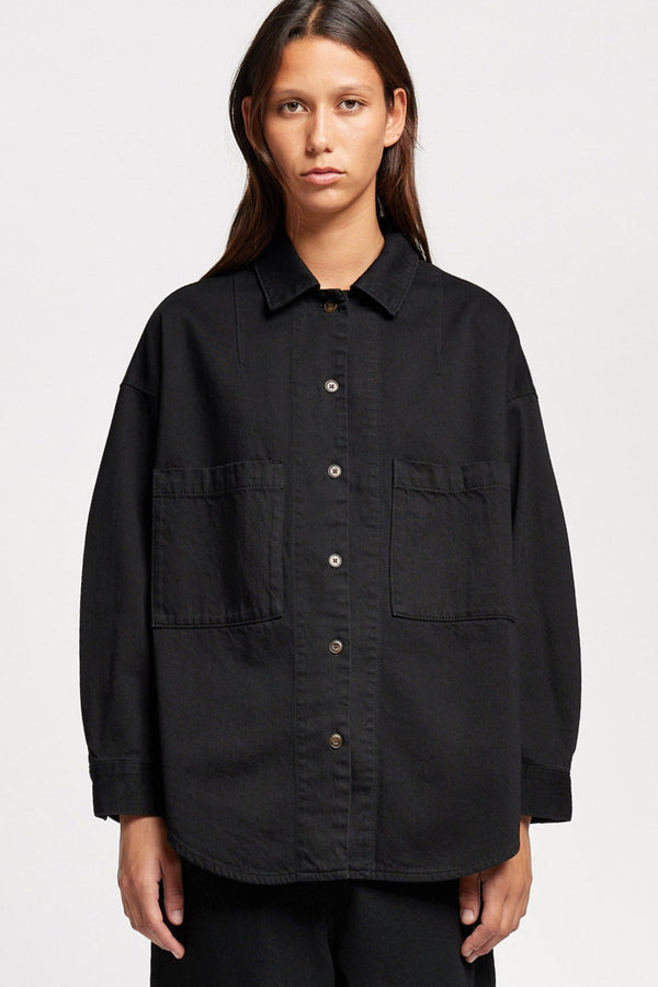 Front view of model wearing the Region oversized denim shirt in Black, featuring utility chest pockets.