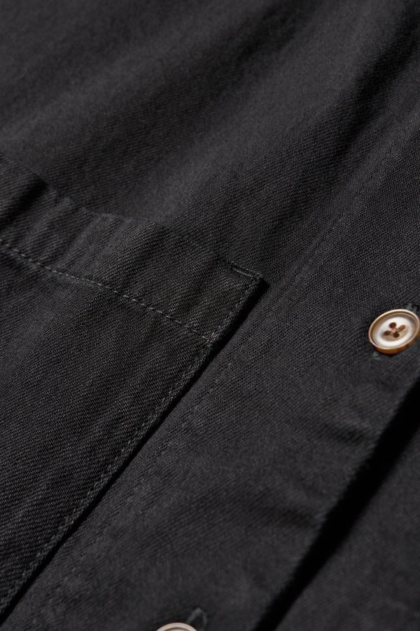 Close up detail shot of front buttons and pocket of the Region oversized denim shirt in black, featuring utility chest pockets.