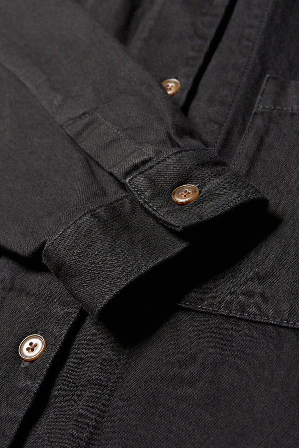 Close up detail cuff and button shot of the Region oversized denim shirt in black, featuring utility chest pockets.
