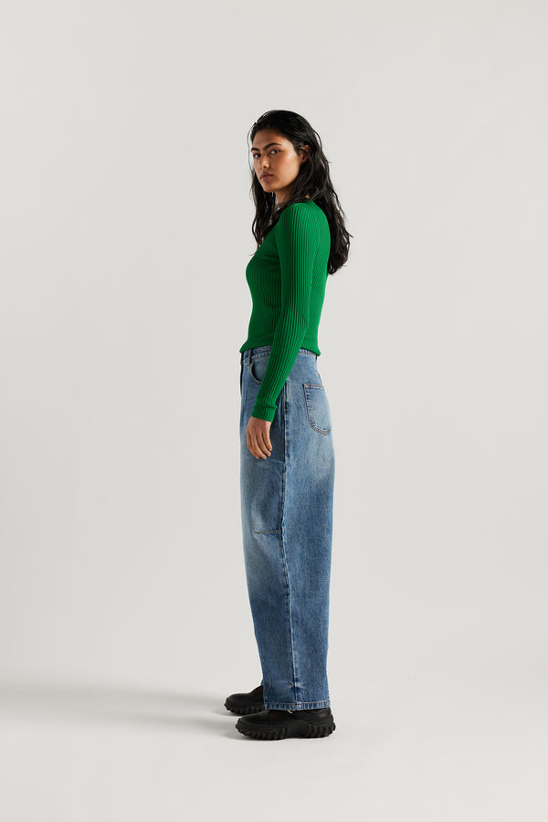 Side view of model in the the Reset Jean, a darted relaxed baggy jean - in mid blue fade