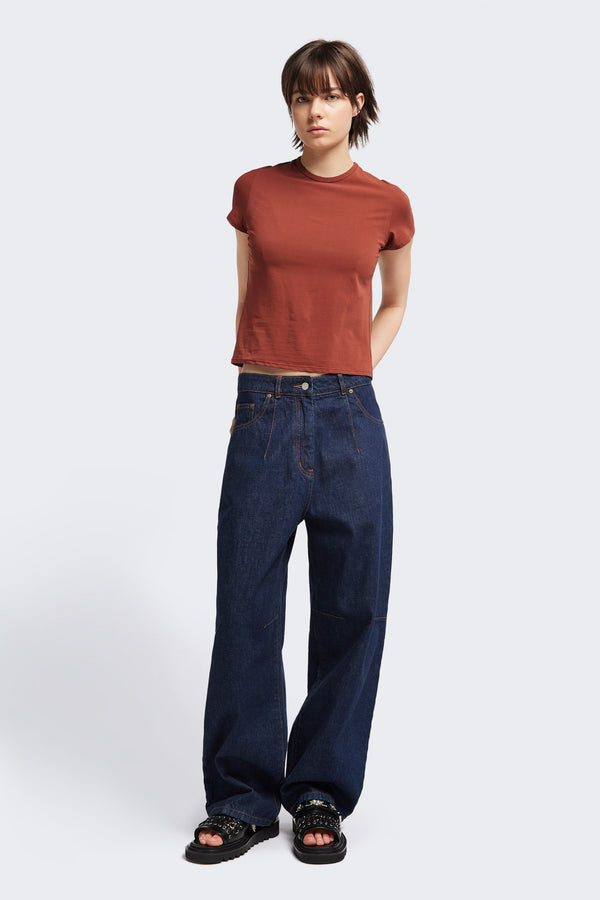 Font view of the model in The Reset Jean Indigo is a relaxed baggy jean featuring two darts at the centre front waistline and darts across the knee.  