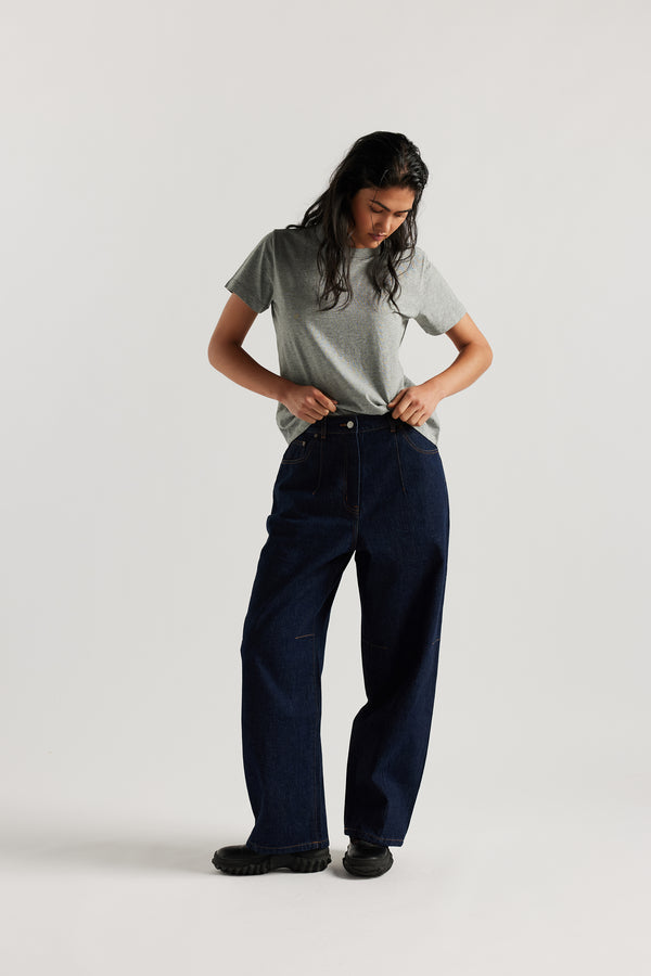 Font view of the model in The Reset Jean Indigo is a relaxed baggy jean featuring two darts at the centre front waistline and darts across the knee.  