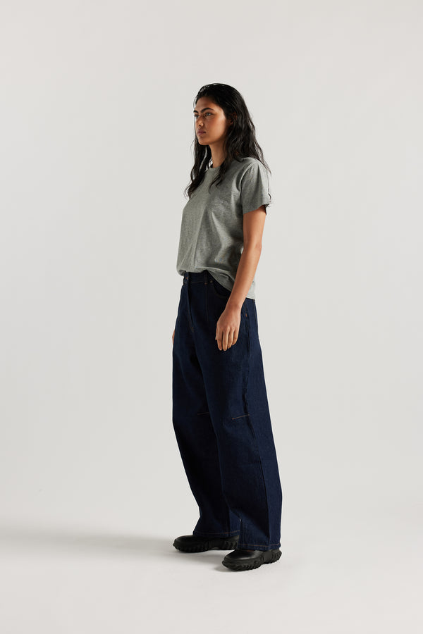 Font view of the model in The Reset Jean Indigo is a relaxed baggy jean featuring two darts at the centre front waistline and darts across the knee.  