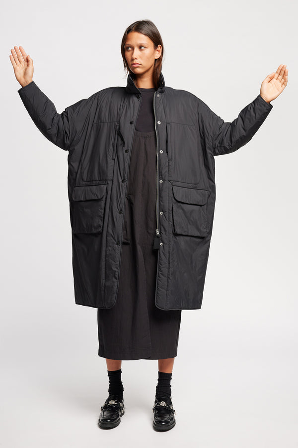 Font view on model of the oversized Restore Coat in Black, showcasing  relaxed silhouette and clean lines
