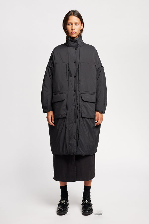 Font view on model of the oversized Restore Coat in Black, showcasing  relaxed silhouette and clean lines
